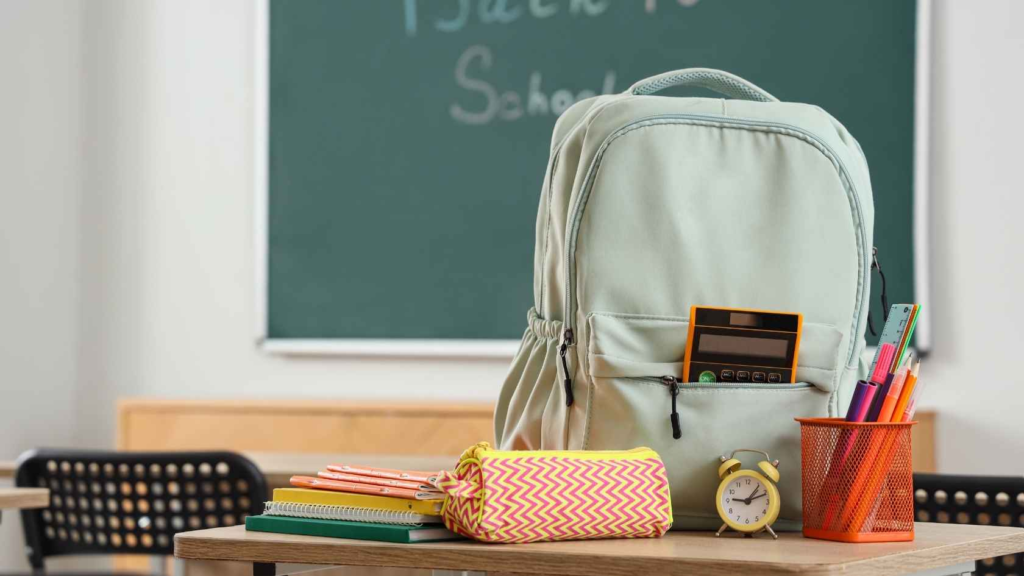 Backpack and school supplies on a classroom desk for back-to-school preparation.