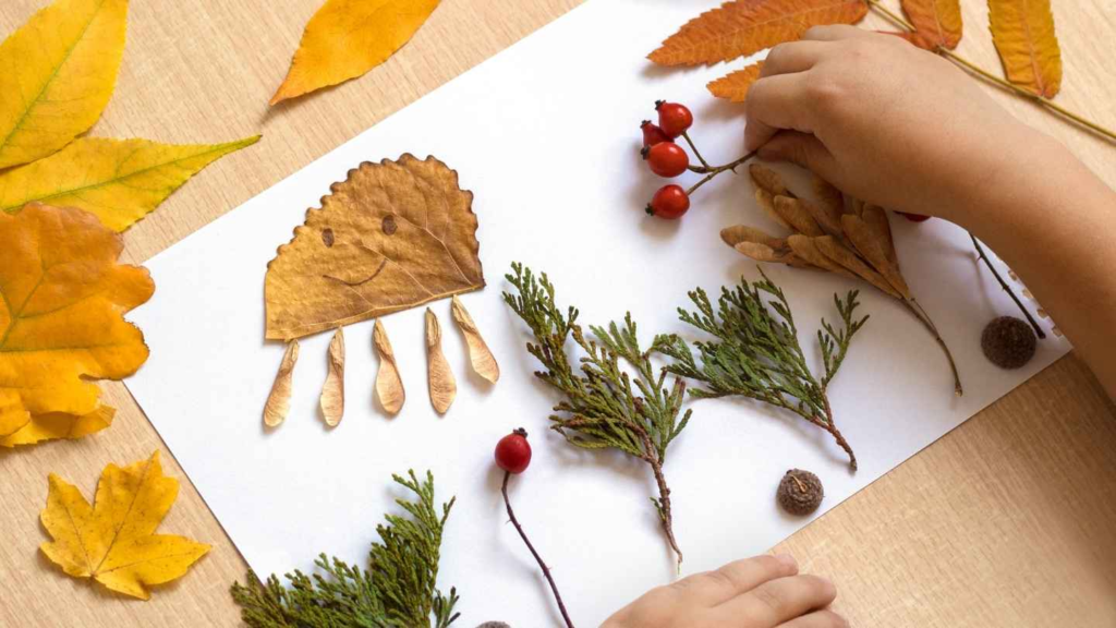 Child creating a fall craft with leaves, berries, twigs, and other natural materials.