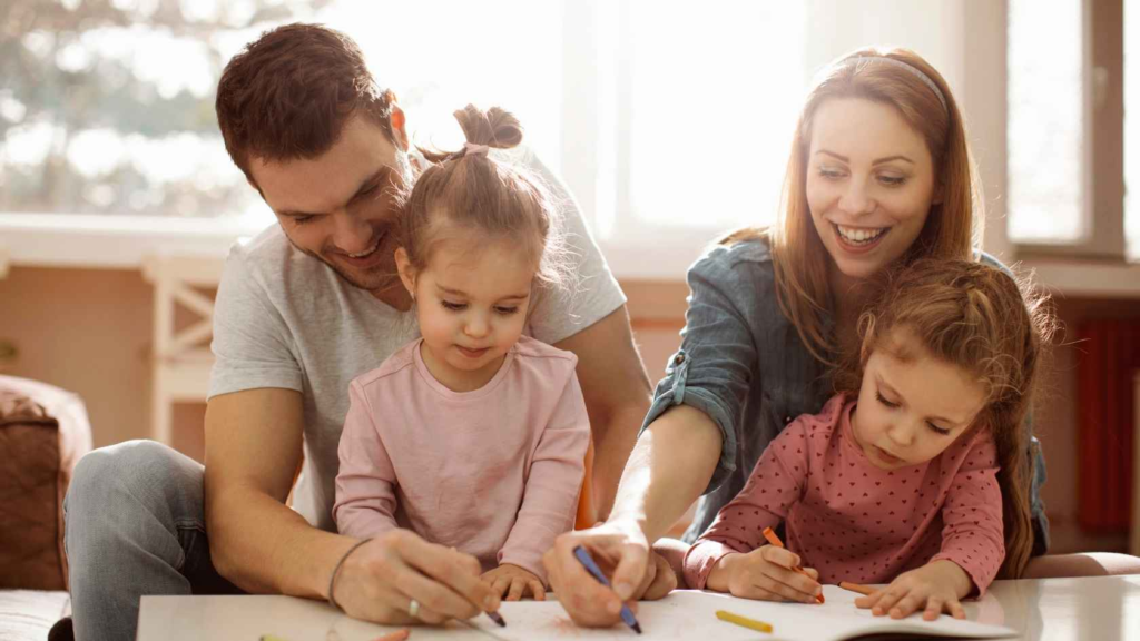 Parents drawing with young children during a family learning activity at home.