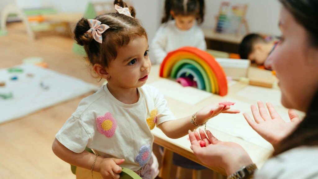Preschool-aged child interacting with a teacher during a hands-on classroom activity.