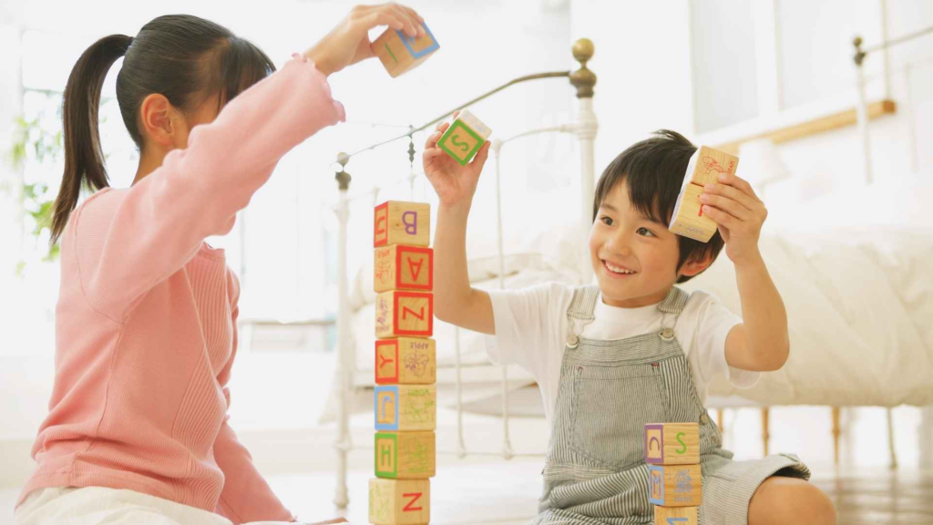 Two young children playing with wooden blocks together during a learning activity.