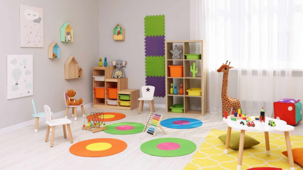 Bright preschool classroom with colorful rugs, toys, shelves, and child-sized furniture.