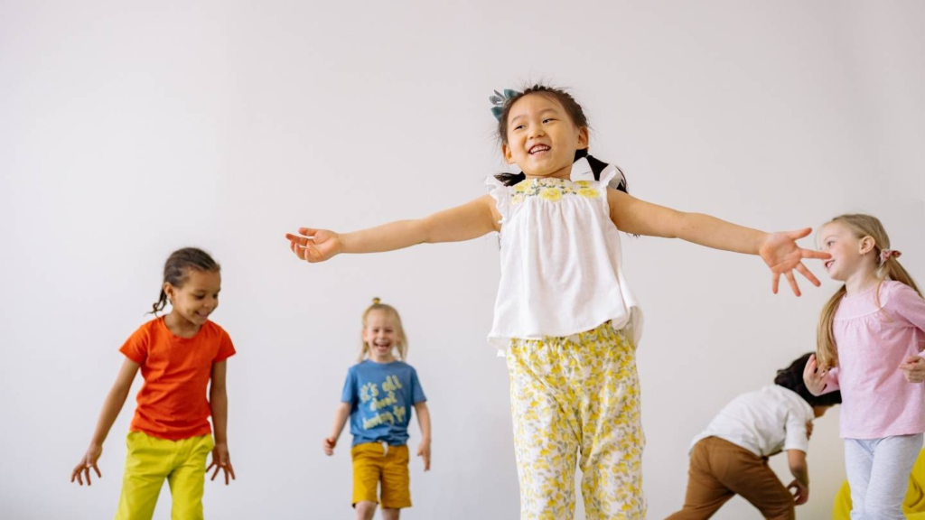 Young children dancing and moving during a group music and movement activity.