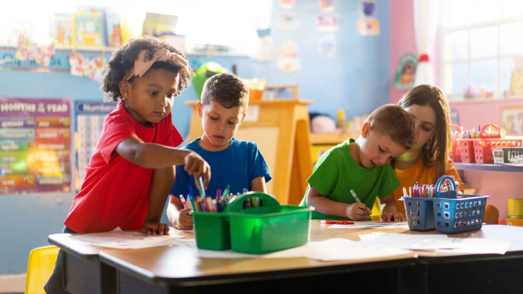Preschool children sharing art supplies during a classroom activity.