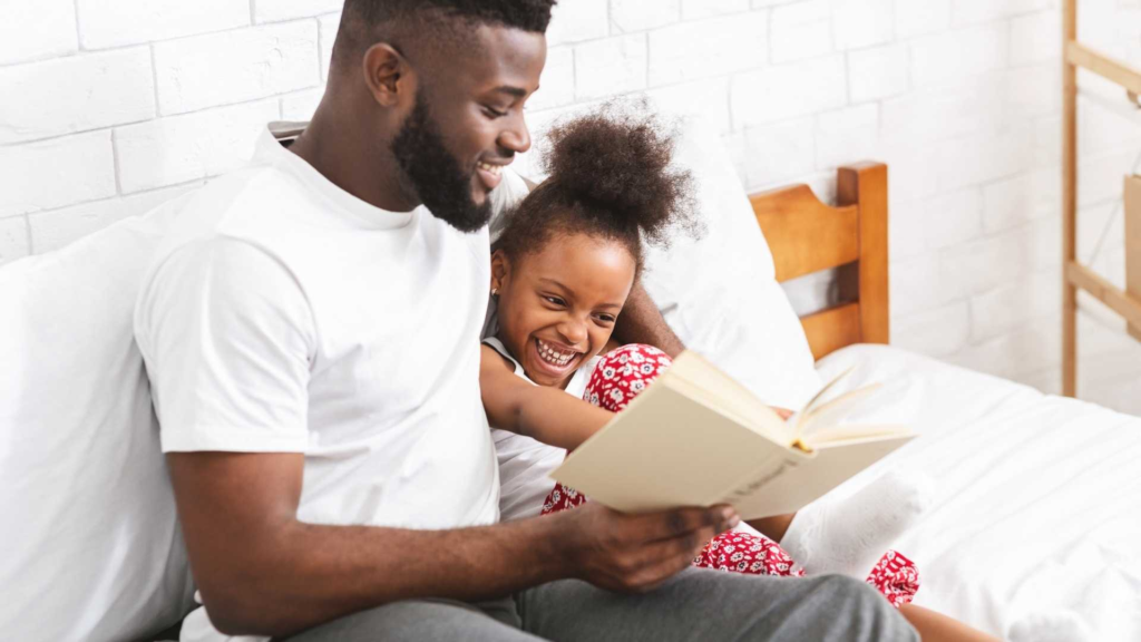 Father reading a book with his young daughter during storytime at home.